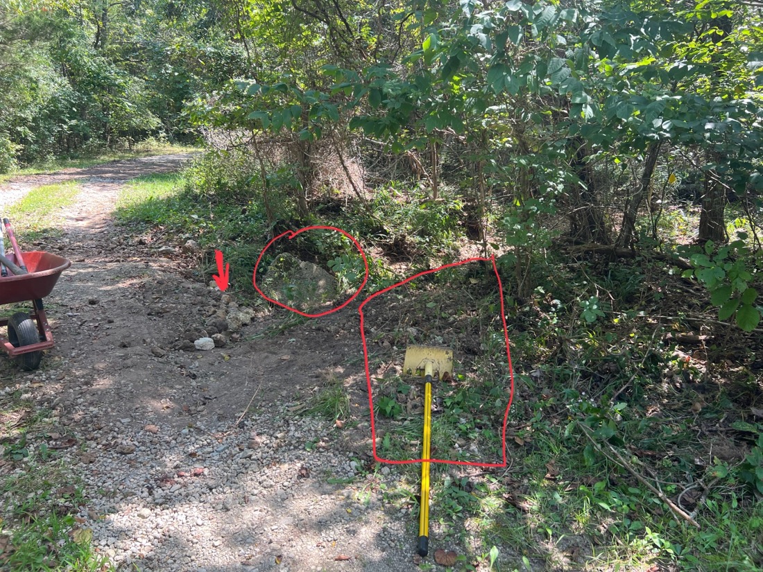 A photo with red markings showing a concrete block and a yellow tool near a creek